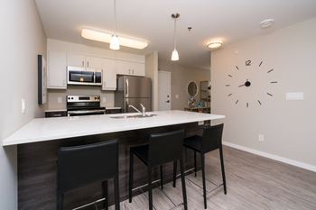 A kitchen with a bar area and a clock on the wall.